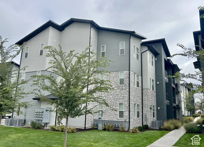 Multi-level exterior featuring a stone veneer facade, horizontal siding, black trim, and a concrete walkway