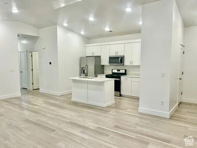 Kitchen featuring white cabinetry, an island with a sink, wood-finish flooring, recessed lighting, and stainless steel appliances