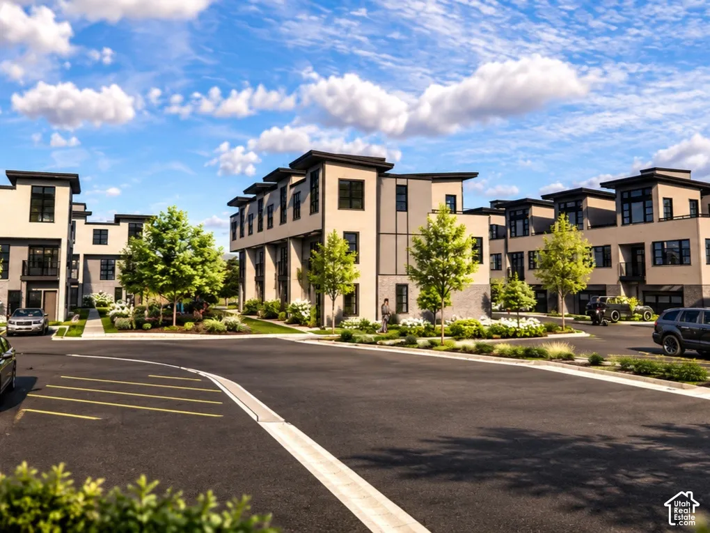Multi-unit residential complex featuring modern architecture, flat rooflines, stone and stucco siding, private balconies, and asphalt-paved surface parking