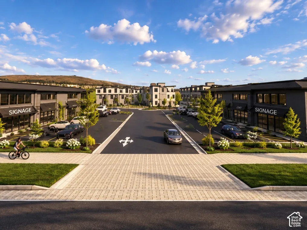 Commercial complex featuring dark-toned masonry facades, expansive paved parking, paved pedestrian walkways, and manicured landscaping with mountain backdrop