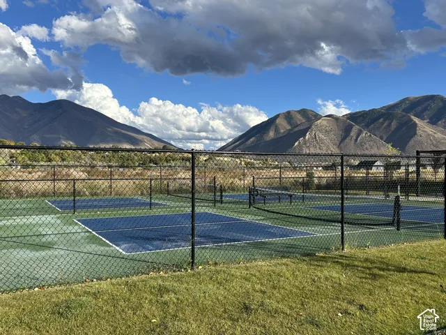 Pickleball courts with blue surfacing, chain-link perimeter fencing, and mountain backdrop