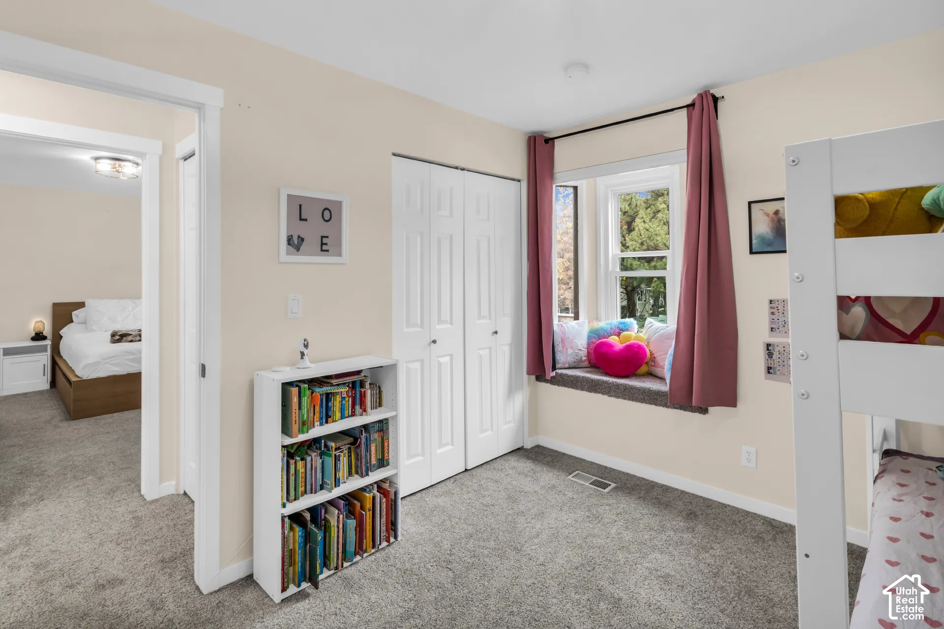 Bedroom featuring carpeted flooring, built-in dual-panel closet doors, and a recessed window nook with a bench seat