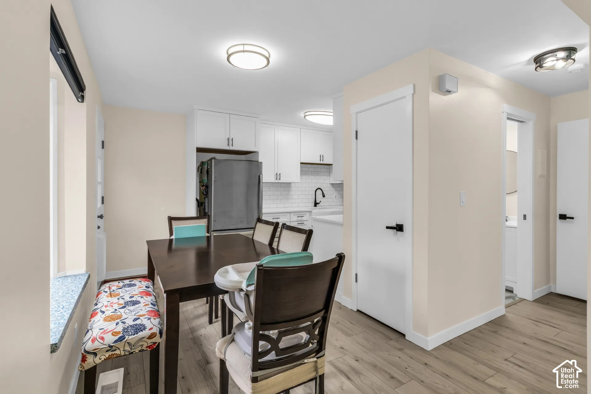 Kitchen area featuring white shaker-style cabinetry, a white subway tile backsplash, matte black hardware, and wood-finish flooring