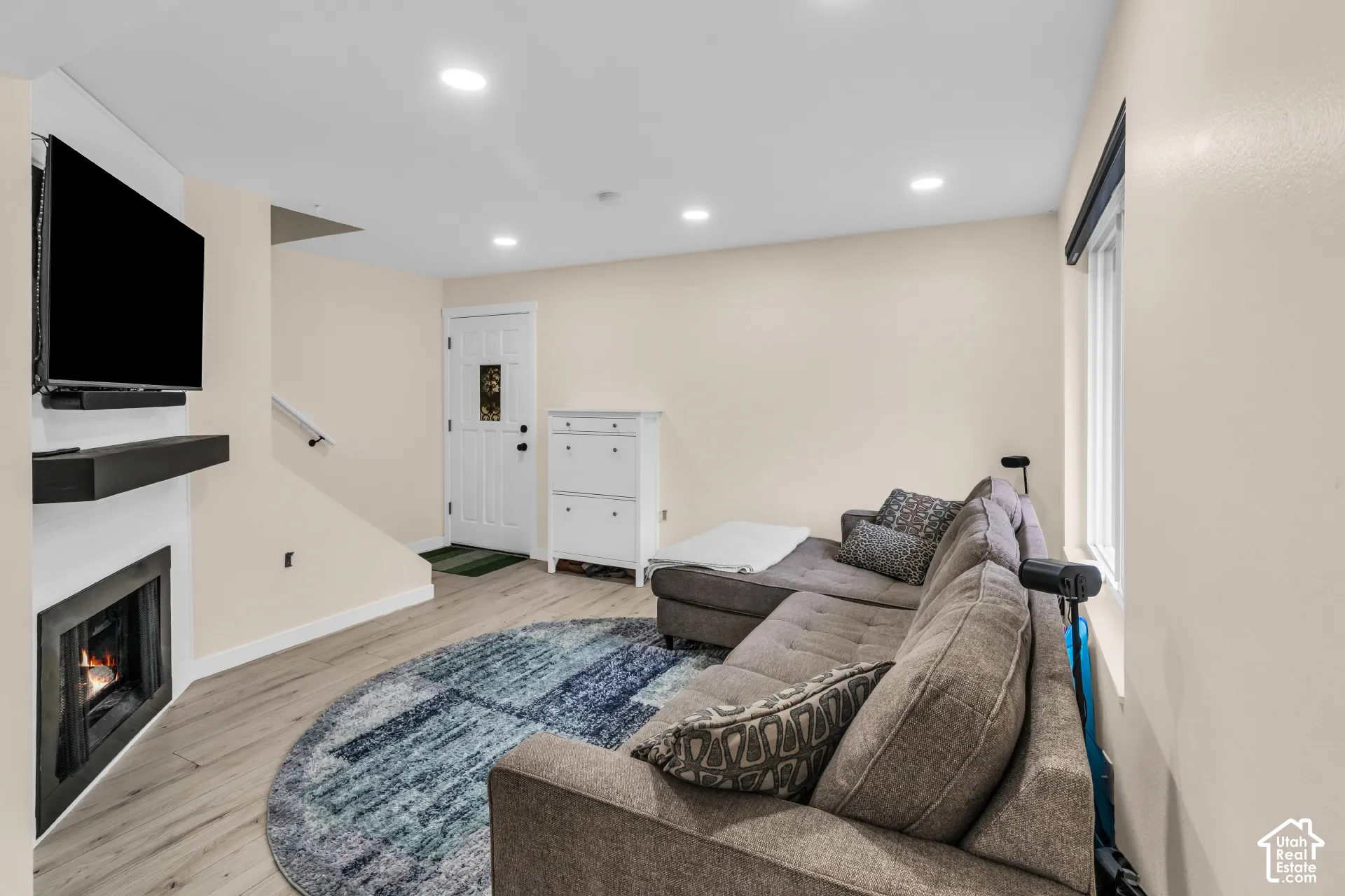 Interior featuring wood-finish flooring, recessed lighting, a fireplace with a minimalist surround, and an exterior door with decorative glass inlay