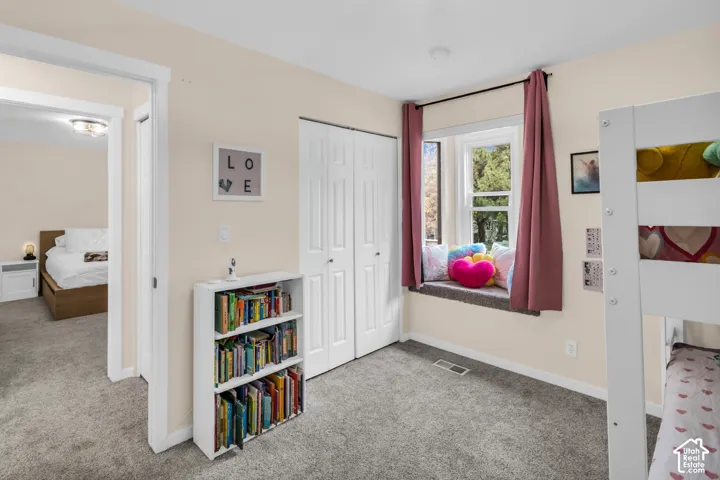 Bedroom featuring carpeted flooring, built-in dual-panel closet doors, and a recessed window nook with a bench seat
