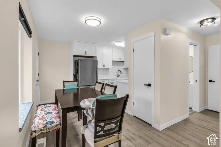Kitchen area featuring white shaker-style cabinetry, a white subway tile backsplash, matte black hardware, and wood-finish flooring