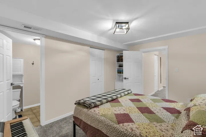 Neutral interior featuring neutral wall paint, carpeted flooring, built-in shelving, white six-panel interior doors, and a geometric flush-mount light fixture