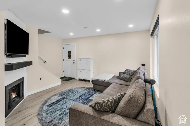 Interior featuring wood-finish flooring, recessed lighting, a fireplace with a minimalist surround, and an exterior door with decorative glass inlay