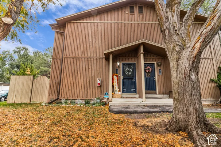 Vertical siding exterior with dual entrance doors, covered porch, and wood-finish privacy fencing