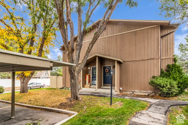 Exterior facade featuring vertical siding, covered entryway, and asphalt-paved carport
