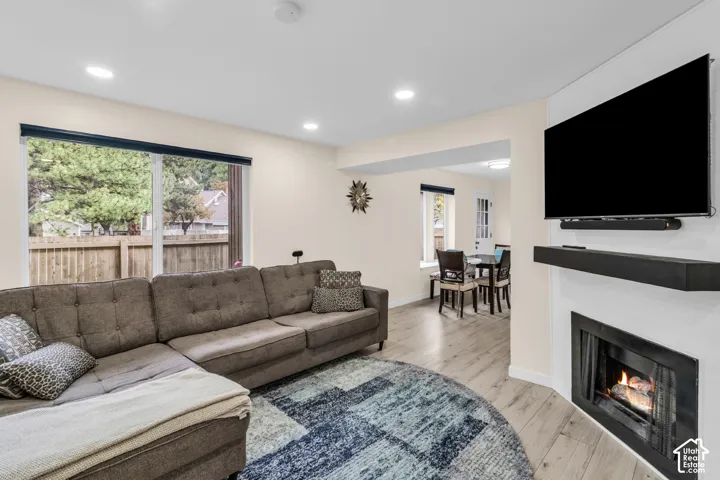 Living area featuring wood-finish flooring, recessed lighting, and a fireplace with a black surround and built-in mantel
