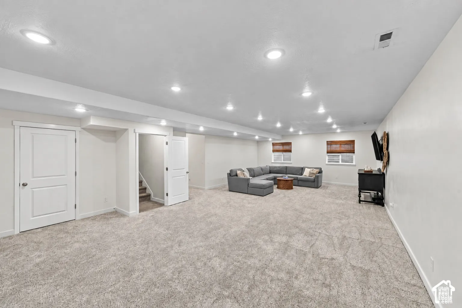 Open-concept interior featuring neutral wall tones, recessed lighting, wall-to-wall carpeting, and multiple windows