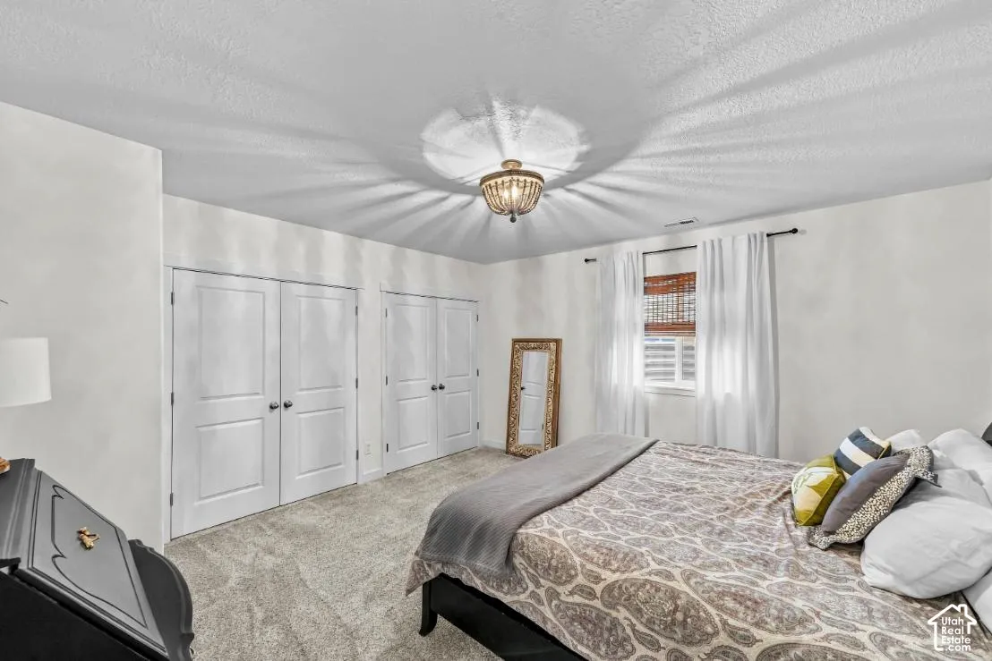Room featuring plush carpeting, double-door closets, and a decorative bead-accented ceiling light fixture