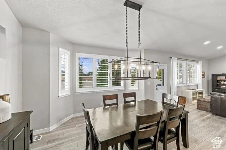 Dining area featuring wood-finish flooring, plantation shutters, and a rectangular multi-light pendant chandelier