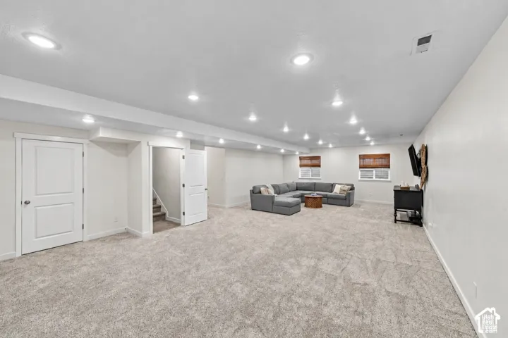 Open-concept interior featuring neutral wall tones, recessed lighting, wall-to-wall carpeting, and multiple windows