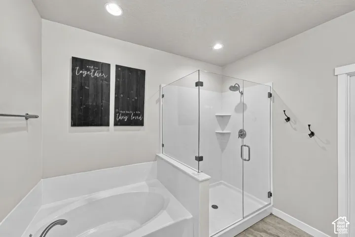 Soaking tub with a white surround and a glass-enclosed shower featuring chrome fixtures and built-in shelving
