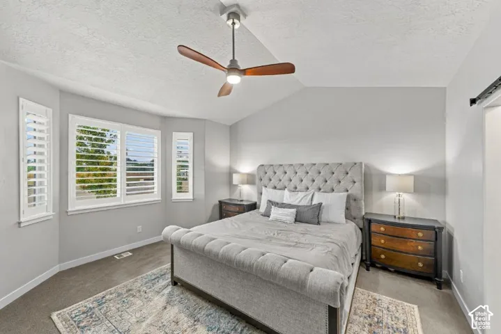 Vaulted ceiling with a centrally mounted three-blade fan, large multi-pane windows, and white plantation shutters