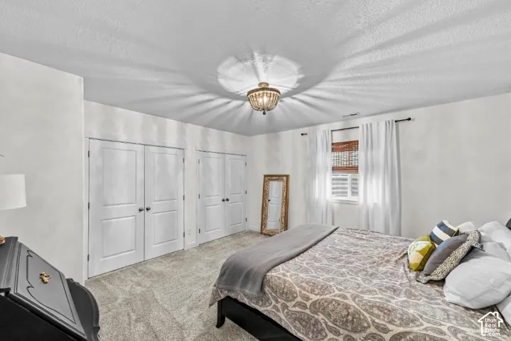 Room featuring plush carpeting, double-door closets, and a decorative bead-accented ceiling light fixture