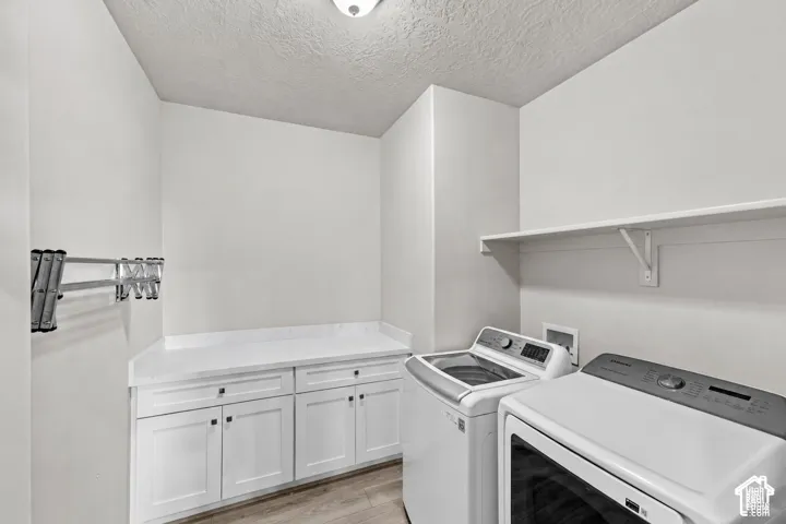 Dedicated laundry area featuring white shaker-style cabinetry, solid-surface countertop, mounted drying rack, and open shelving