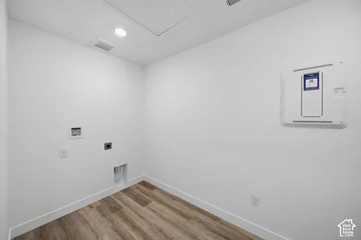 Dedicated utility area featuring wood-finish flooring, recessed lighting, and wall-mounted electrical panel