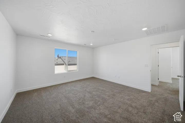 Neutral-toned wall-to-wall carpeting, recessed ceiling lighting, and crisp white wall finishes