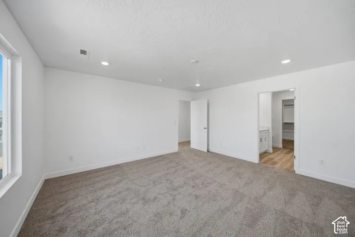 Neutral-toned interior space featuring wall-to-wall carpeting, recessed ceiling lighting, and a multi-panel door