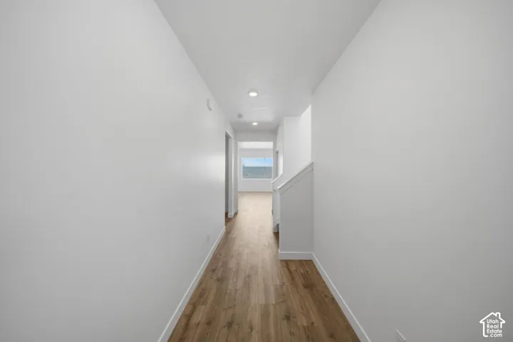 Hallway featuring wood-finish flooring, recessed ceiling lighting, and neutral wall tones