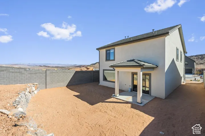 Two-story residence featuring a covered patio, xeriscaped yard, natural stone retaining wall, and concrete block perimeter fencing