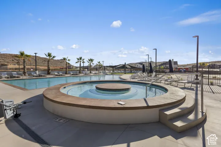 Community swimming pool featuring a circular spa, concrete decking, and palm tree landscaping