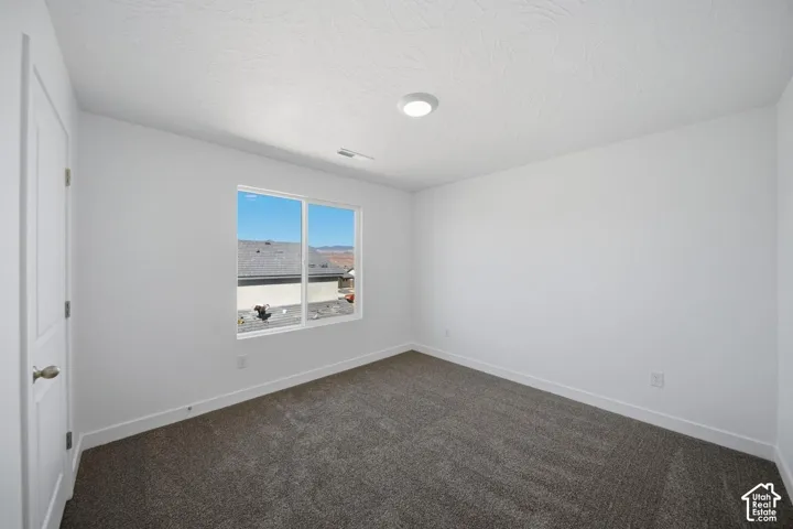 Neutral-toned wall-to-wall carpeting, crisp white walls, flush-mount ceiling lighting, and a window with exterior mountain scenery