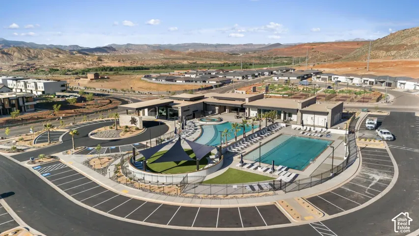 Community recreation facility featuring a swimming pool, lap pool, spa, turf area with shade sails, and paved parking lot