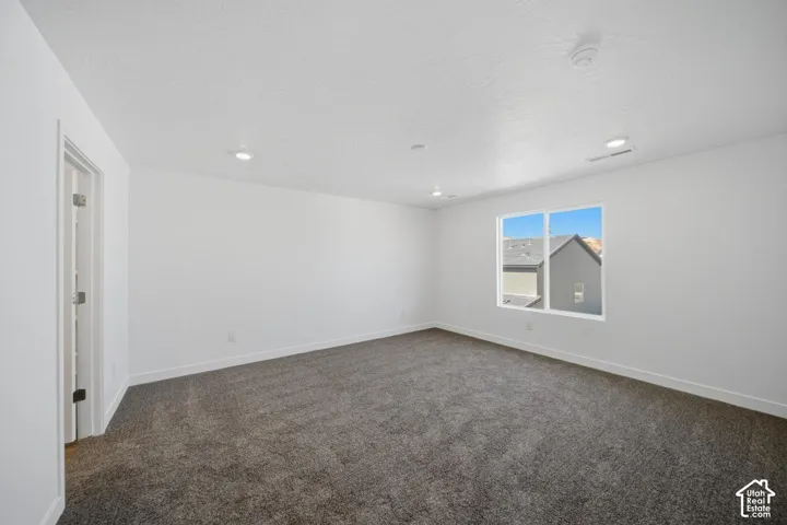 Neutral-toned wall-to-wall carpeting, recessed ceiling lighting, and large window with natural light