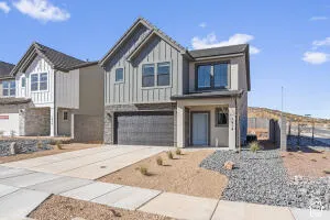 Two-story exterior featuring vertical board-and-batten siding, stone veneer accents, multi-pane windows, and a concrete driveway