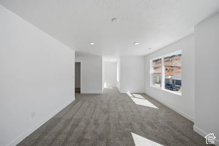 Neutral-toned carpeting, recessed ceiling lighting, and large windows with stone ridge outcroppings