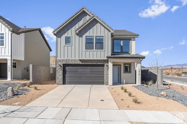 Two-story exterior featuring vertical board-and-batten siding, stone veneer accents, an attached two-car garage, and a covered entryway