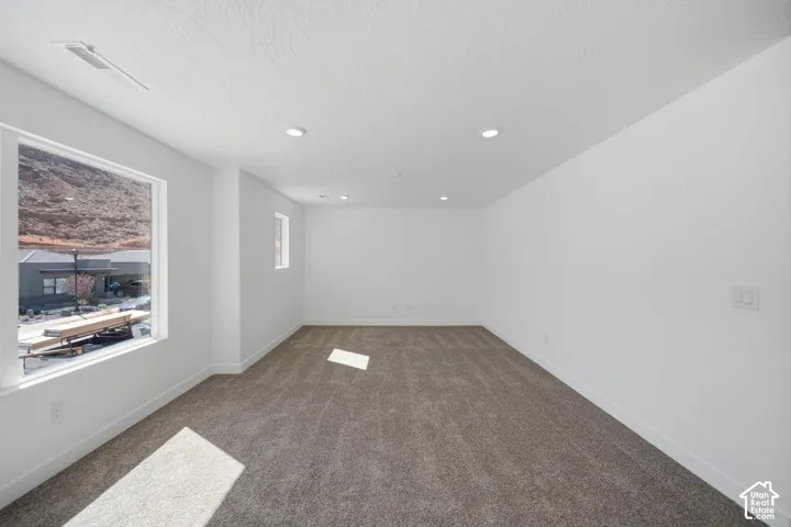 Neutral-toned wall-to-wall carpeting, recessed ceiling lighting, and large picture windows