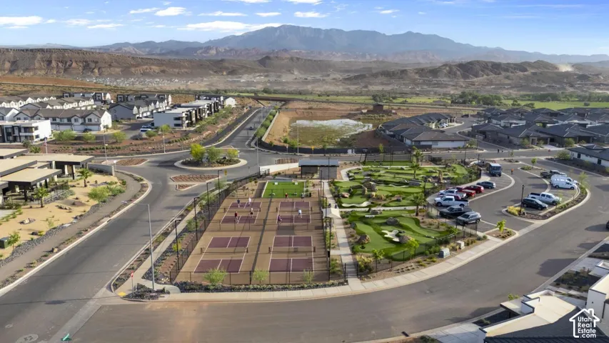 Aerial view of community amenities including multiple pickleball courts, a miniature golf course, paved parking areas, and expansive mountain scenery