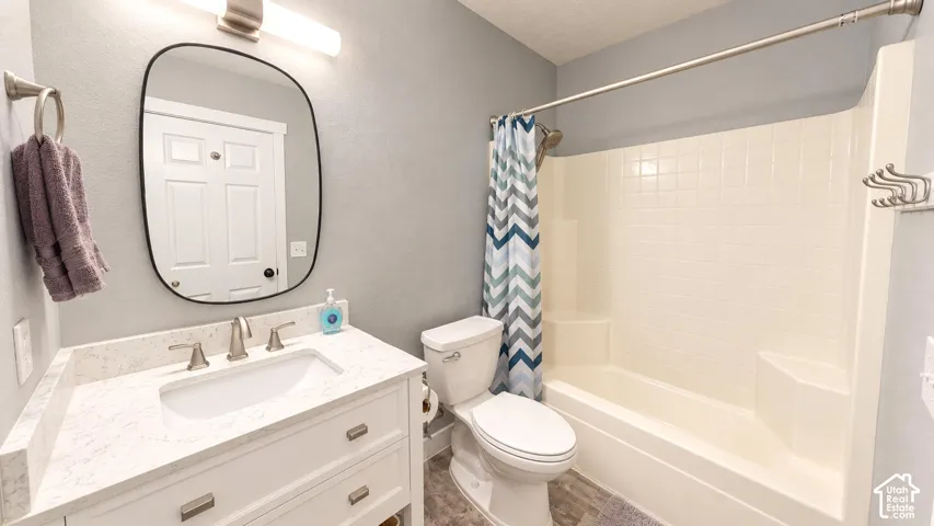 Bathroom featuring a white vanity with a stone-composite countertop, an integrated rectangular sink, a rounded-edge vanity mirror, and a built-in tub-shower combination with tiled surround
