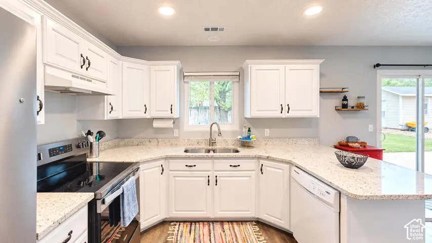 Kitchen featuring white cabinetry, light-toned speckled countertops, stainless steel electric range, undermount double-basin sink, and recessed ceiling lighting