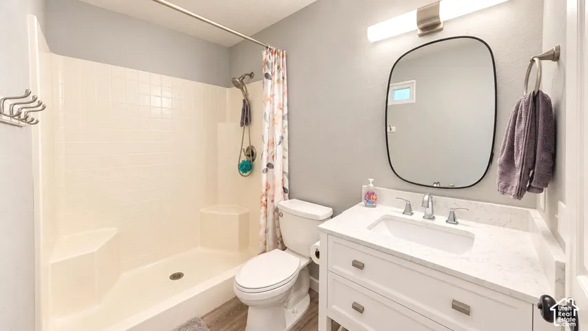 Bathroom featuring a white vanity with a neutral stone-finish countertop, undermount sink, rounded rectangular mirror, and a tub-shower combination with built-in seating