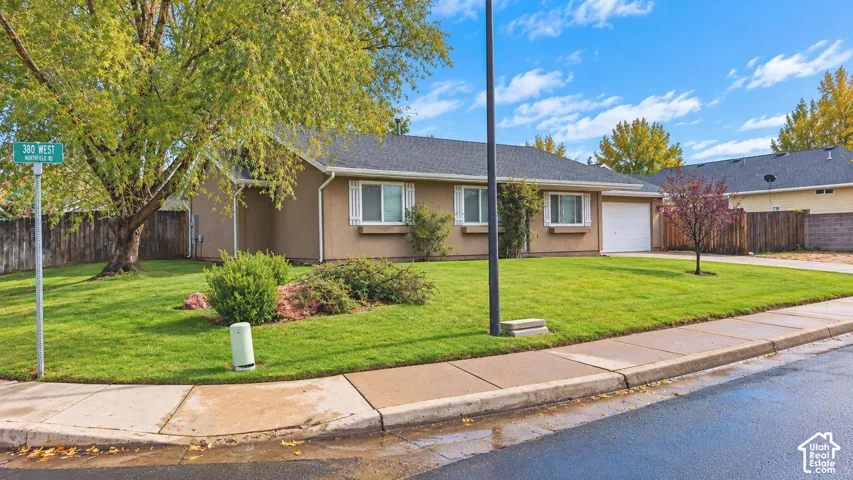 Single-level exterior featuring a shingled roof, neutral-toned siding, white window shutters, and an attached single-car garage situated on a corner lot