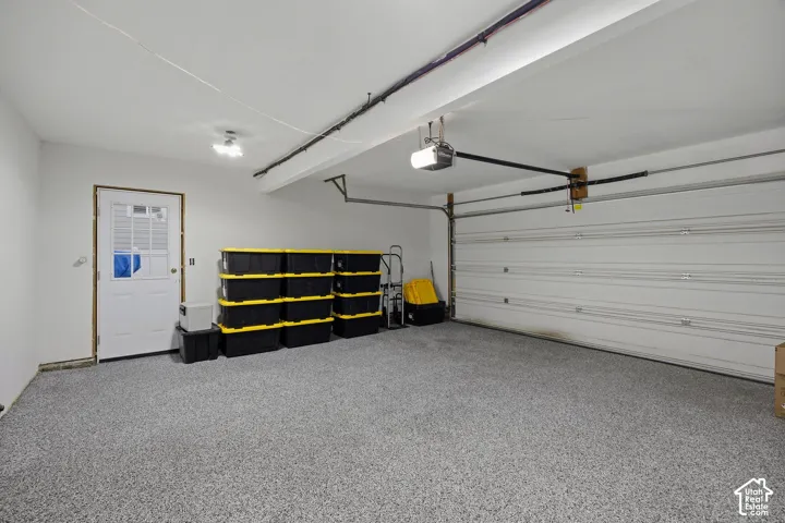 Garage space featuring an epoxy-coated floor, white paneled garage door, and a dedicated entry door with a multi-pane glass insert