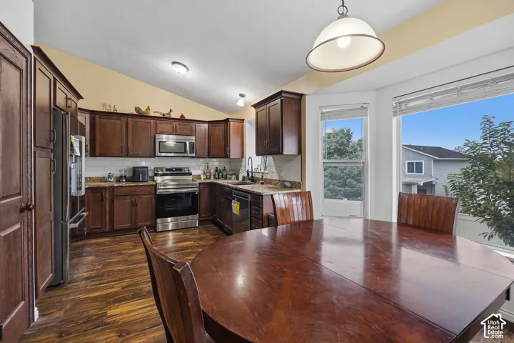 Kitchen featuring wood cabinetry, stone-surface countertops, subway tile backsplash, stainless steel appliances, and wood-finish flooring