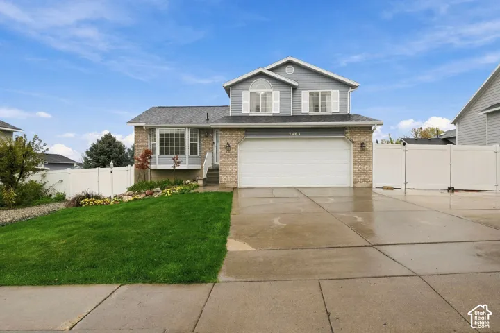 Two-story exterior featuring a brick and horizontal siding facade, an attached two-car garage, an arched window, and a white privacy fence