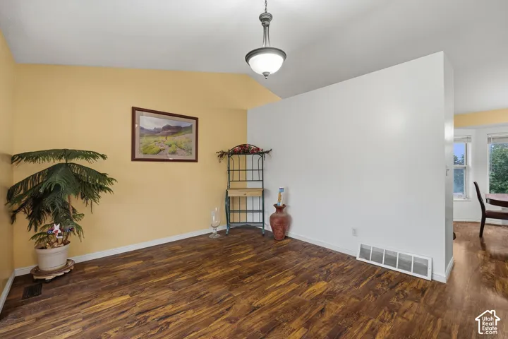 Vaulted ceilings, wood-finish flooring, and a pendant light fixture