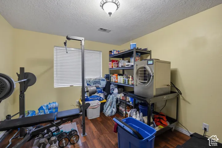 Room featuring wood-finish flooring, a window with horizontal blinds, and a flush-mount ceiling light fixture