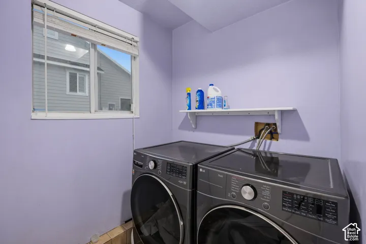 Laundry area featuring a window with horizontal blinds and a mounted white shelf