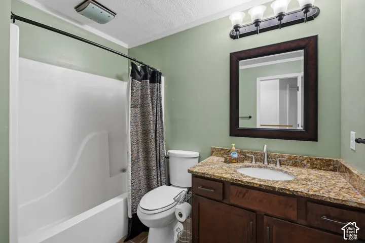 Bathroom featuring a wood-tone vanity, speckled stone-surface countertop with an integrated oval basin, a dark-finish framed mirror, and a white molded tub-shower surround