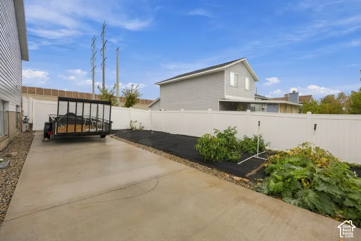 Concrete side yard with white vinyl privacy fencing and landscape fabric ready for planting