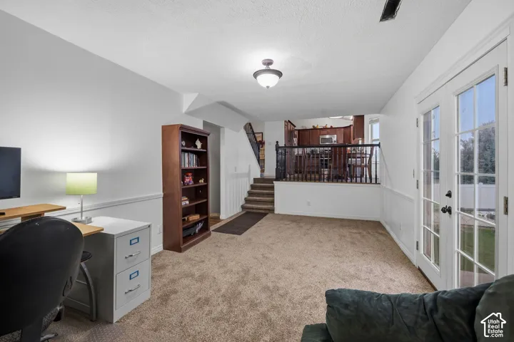 Carpeted interior featuring French doors with glass panes, decorative chair rail molding, and a built-in wooden staircase railing